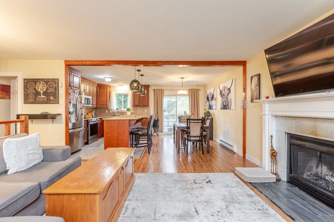 Living area featuring a baseboard heating unit, light wood-style flooring, and a tile fireplace | Image 6