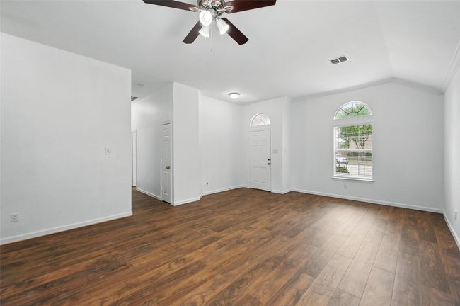 Unfurnished room with ceiling fan, dark wood-type flooring, baseboards, and lofted ceiling | Image 27