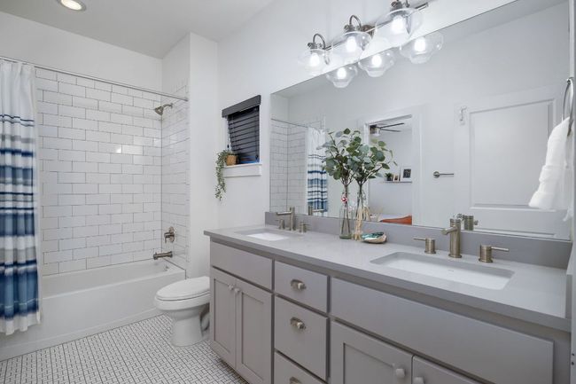 Shared full bath featuring double vanity, tile floor, dual vanity, and shower / tub combo. | Image 9