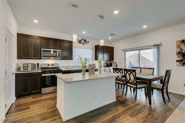Kitchen featuring dark wood-type flooring, dark brown cabinetry, stainless steel appliances, and recessed lighting | Image 7