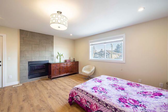 Bedroom featuring visible vents, a tiled fireplace, wood finished floors, recessed lighting, and baseboards | Image 17