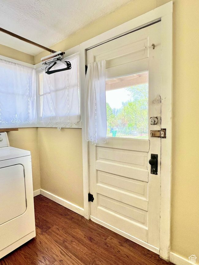 Washroom with a textured ceiling, washer / dryer, baseboards, dark wood-style flooring, and laundry area | Image 26