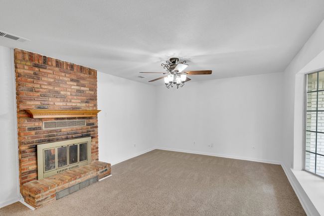 Unfurnished living room featuring baseboards, a ceiling fan, carpet flooring, and a fireplace | Image 10
