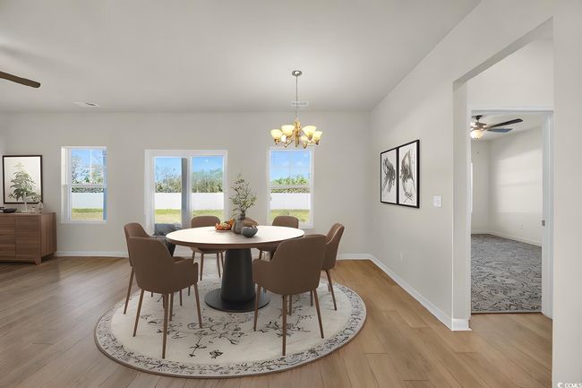 Dining room featuring light wood finished floors, ceiling fan with notable chandelier, and baseboards | Image 6