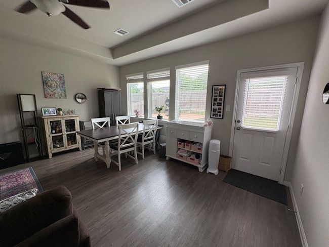 Dining space with wood finished floors, a ceiling fan, baseboards, and a tray ceiling | Image 4