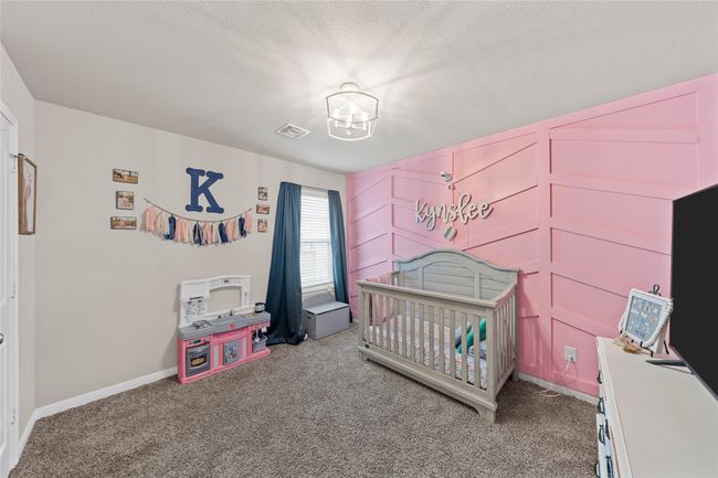 Carpeted bedroom featuring a chandelier, a textured ceiling, a crib, and baseboards | Image 8