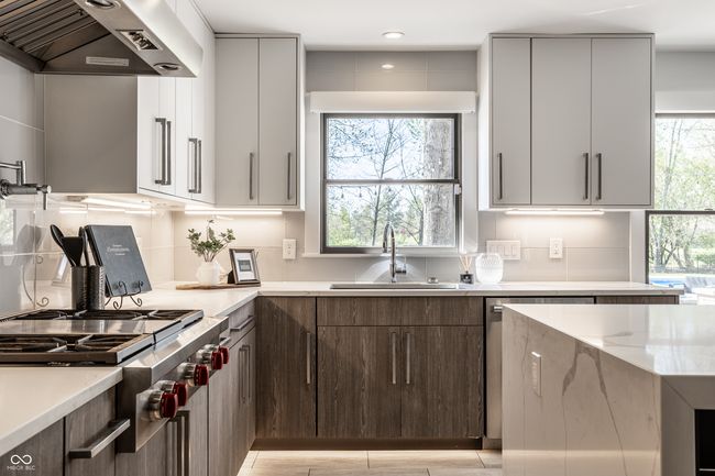 kitchen featuring modern cabinets, a sink, stainless steel gas stovetop, and under cabinet range hood | Image 15