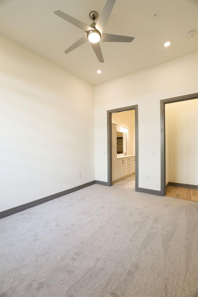 Unfurnished bedroom with ceiling fan, connected bathroom, and light carpet | Image 17