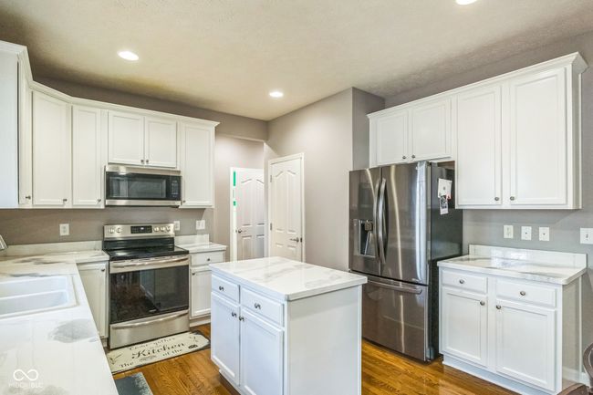 kitchen with stainless steel appliances, dark wood-style flooring, white cabinetry, recessed lighting, and a kitchen island | Image 14