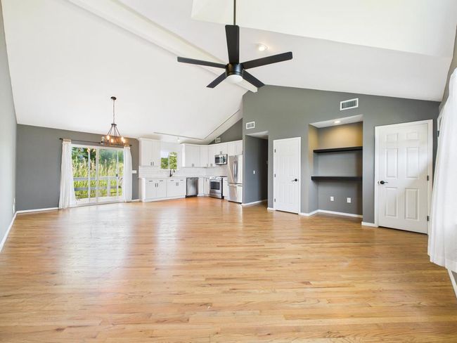 Unfurnished living room with ceiling fan, light wood finished floors, and high vaulted ceiling | Image 11