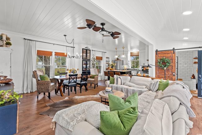 Living area featuring a barn door, a ceiling fan, light wood-type flooring, a chandelier, and recessed lighting | Image 6