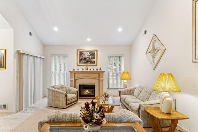 Tiled living area featuring lofted ceiling, visible vents, and a glass covered fireplace | Image 7