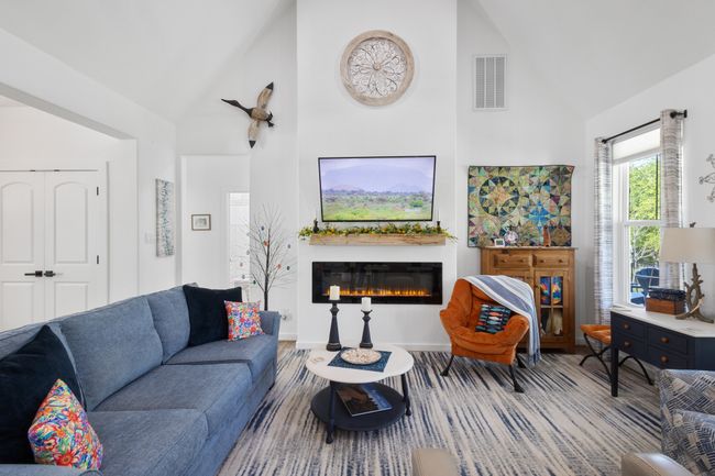 Living room with a glass covered fireplace, high vaulted ceiling, and visible vents | Image 9