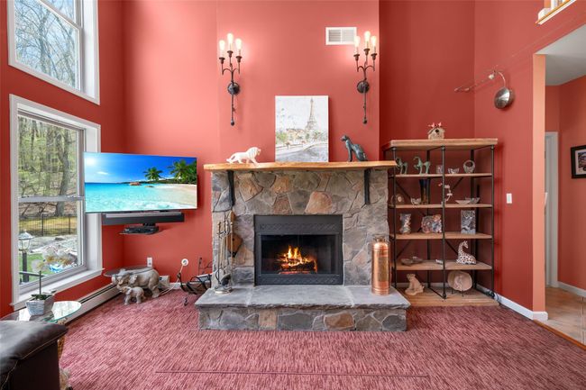 Living room featuring a towering ceiling, baseboards, a fireplace, and visible vents | Image 11
