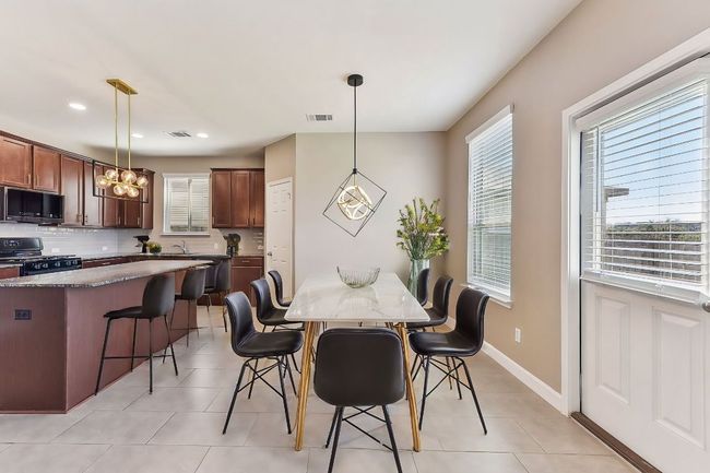Dining room featuring light tile patterned flooring, a notable chandelier, and visible vents | Image 9