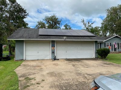 This is a single-story home featuring a detached triple garage with workshop & shower bathroom, white doors and a large solar panel installation on the roof. The driveway is spacious, and the house is set in a neighborhood with mature trees. | Image 2