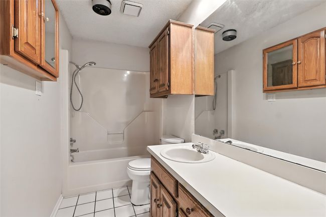 Full bathroom featuring vanity, bathtub / shower combination, tile patterned floors, and a textured ceiling | Image 30