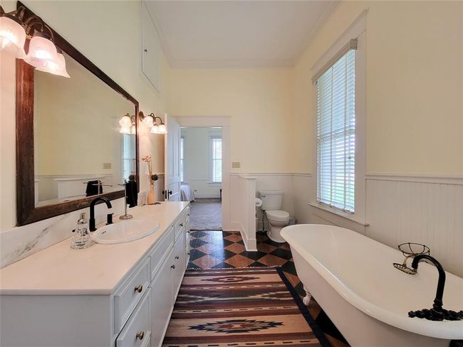 Experience luxury in the primary en-suite with stunning antique hardwood floors, elegant double vanities, and a relaxing soaking tub. | Image 19