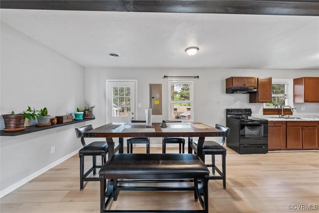 Dining space with electric panel, visible vents, light wood finished floors, and baseboards | Image 13