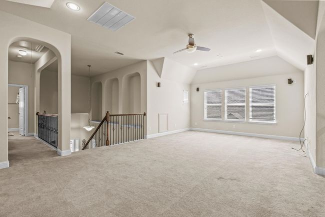 Empty room featuring carpet floors, a ceiling fan, baseboards, lofted ceiling, and arched walkways | Image 22