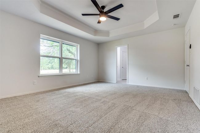 Spare room featuring a tray ceiling, light carpet, and ceiling fan | Image 19