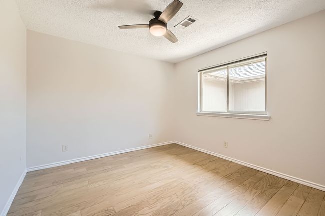 Bedroom with a textured ceiling, light wood finished laminate floors, and a ceiling fan | Image 17