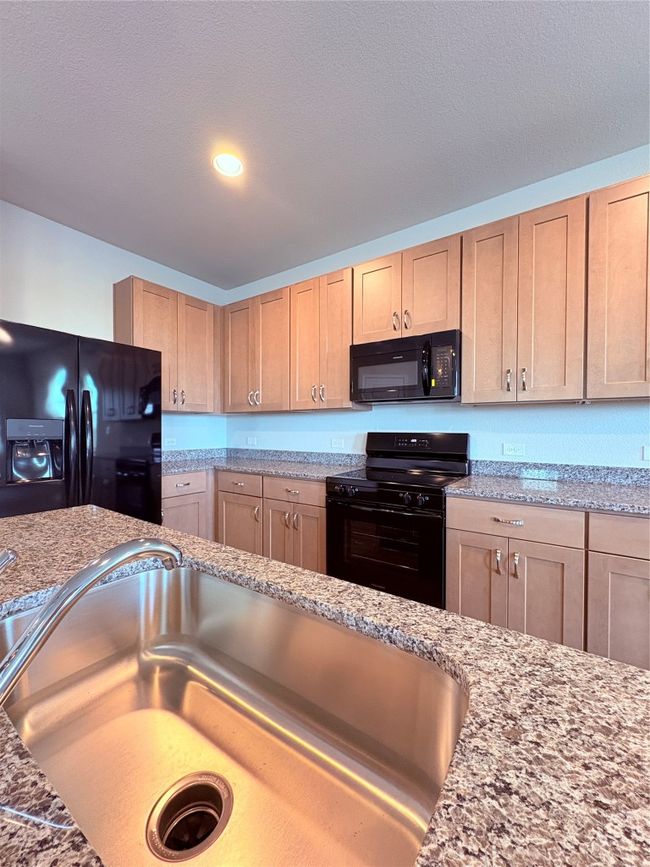 Kitchen with a sink, stove, and fridge | Image 11