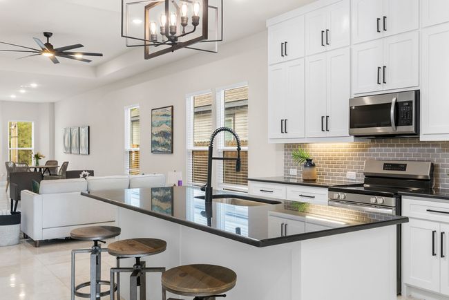 Kitchen featuring open floor plan, decorative backsplash, ceiling fan with notable chandelier, stainless steel appliances, and a sink | Image 5