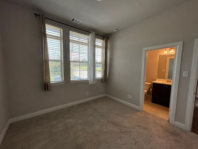 bedroom featuring light colored carpet, baseboards, ensuite bath, and a sink | Image 8