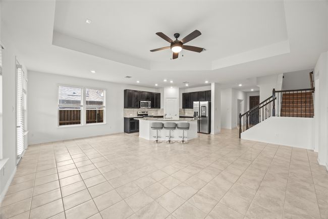 Unfurnished living room featuring a raised ceiling, recessed lighting, a ceiling fan, stairway, and light tile patterned flooring | Image 10