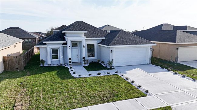 View of front facade featuring stucco siding, concrete driveway, fence, a garage, and a front lawn | Image 6