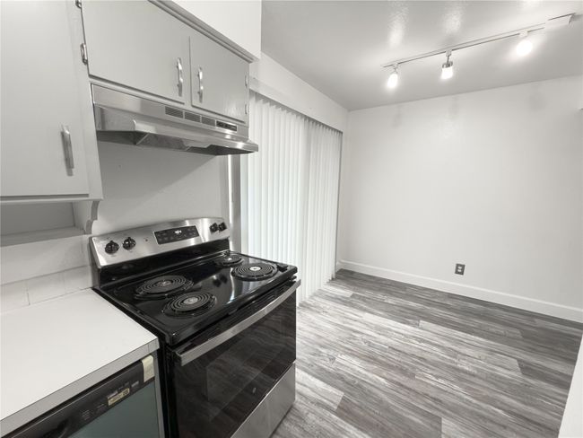 Kitchen featuring dishwasher, rail lighting, stainless steel range with electric stovetop, and hardwood / wood-style flooring | Image 7