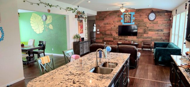 Kitchen with dark wood-style flooring, ceiling fan, light stone countertops, lofted ceiling, and open floor plan | Image 11