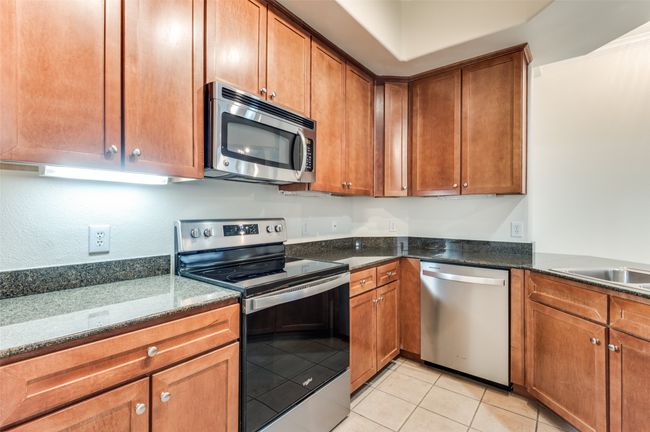 Crisp shaker-style cabinetry pairs seamlessly with sleek granite countertops and premium stainless-steel appliances, all opening up to captivating views of the dining and living areas—creating a chef’s showcase that’s as beautiful as it is functional. | Image 20