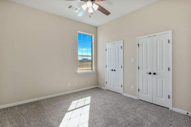 Unfurnished bedroom with carpet flooring, two closets, baseboards, and ceiling fan | Image 31