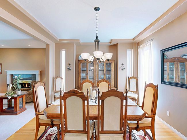 Dining room featuring a chandelier, light wood finished floors, a premium fireplace, and a raised ceiling | Image 14
