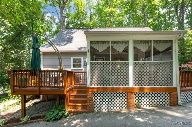 Back of house featuring a sunroom, a shingled roof, a deck, and stairway | Image 42