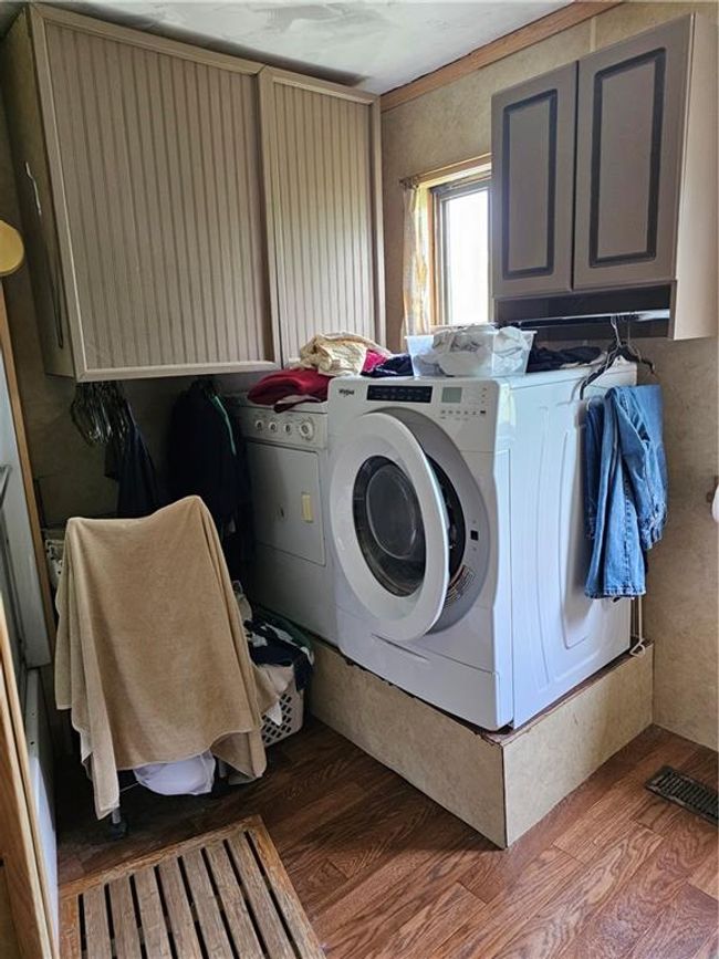 Clothes washing area featuring wood finished floors, washer and dryer, and cabinet space | Image 11
