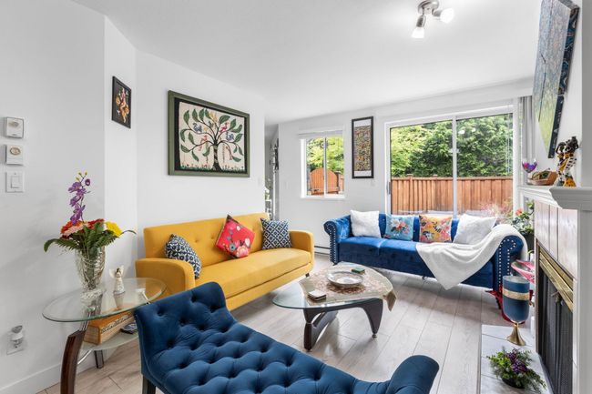 Living area featuring wood finished floors, a baseboard radiator, and a fireplace | Image 8