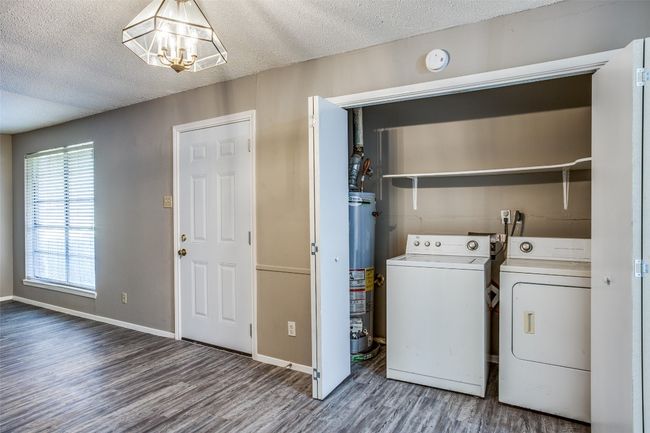 Laundry area with washing machine and clothes dryer, laundry area, an inviting chandelier, gas water heater, and wood finished floors | Image 16