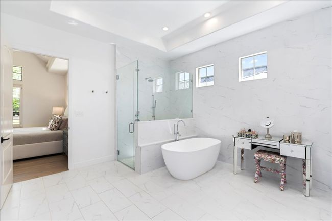 Full bathroom featuring ensuite bath, marble look tiles, a soaking tub, a marble finish shower, and recessed lighting | Image 19