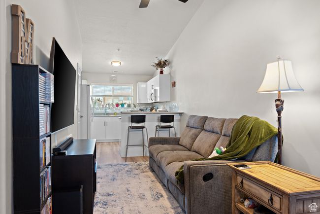 Living room featuring a ceiling fan, light wood-style floors, and lofted ceiling | Image 7