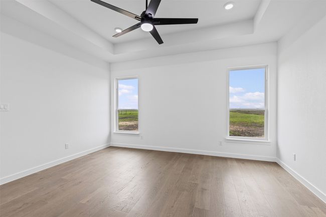 Unfurnished room with baseboards, a raised ceiling, wood finished floors, and a wealth of natural light | Image 27