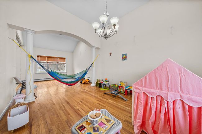 Game room with a baseboard heating unit, vaulted ceiling, ornate columns, arched walkways, and wood finished floors | Image 16