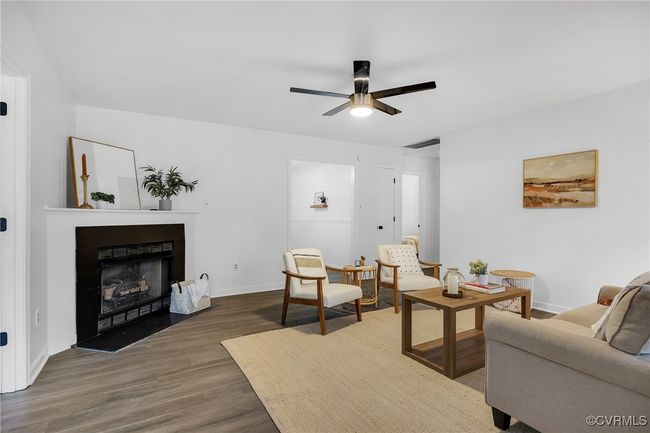Living room featuring ceiling fan, wood finished floors, baseboards, and a fireplace | Image 31