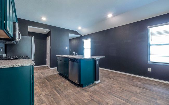 Kitchen with stainless steel dishwasher, an island with sink, dark wood-style floors, lofted ceiling, and stove | Image 7