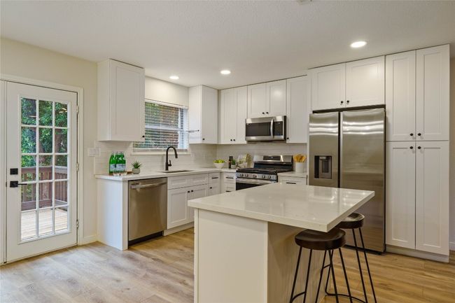 Kitchen featuring appliances with stainless steel finishes, light wood-style floors, decorative backsplash, and a sink | Image 13