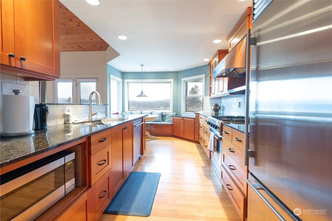 Kitchen with straight grain fir cabinets and oak hardwood floors looking towards the eating nook and view | Image 23