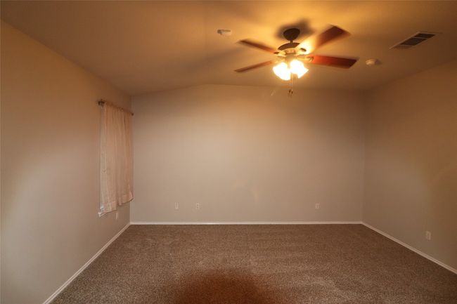 Spare room featuring a ceiling fan, dark colored carpet, and lofted ceiling | Image 21