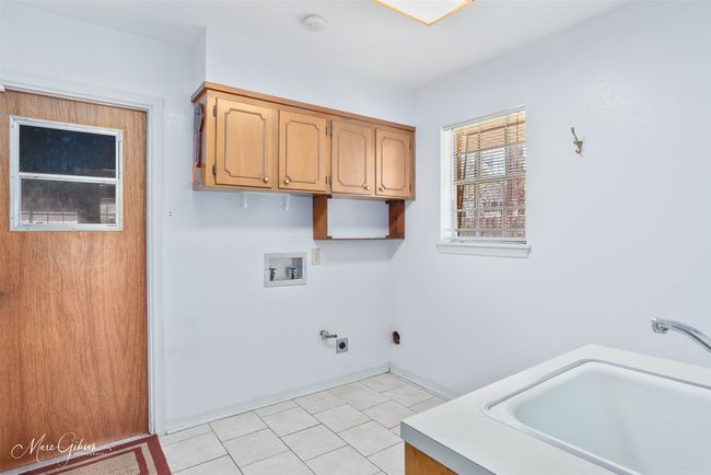 Washroom with hookup for a washing machine, hookup for a gas dryer, light tile patterned flooring, cabinet space, and a sink | Image 18